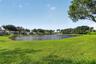 Expansive waterfront lot featuring a large pond, manicured lawn, and mature canopy trees