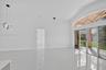 Vaulted ceilings, large-format tile flooring, contemporary circular pendant lighting, and expansive multi-panel sliding glass doors with arched transo