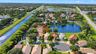 Aerial view of a residential property featuring a tiled roof, situated on a cul-de-sac lot with direct water frontage and mature landscaping