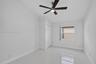 Neutral-toned room featuring high-gloss tile flooring, vaulted ceiling, multi-blade ceiling fan with integrated lighting, and a closet with bifold doo