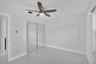 Light-toned tile flooring, ceiling fan with integrated lighting, and sliding mirrored closet doors
