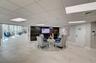 Open-concept space featuring large-format tile flooring, drop ceiling with recessed panel lighting, and a dark wood-finish accent wall with an integra