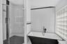 Walk-in glass-enclosed shower with mosaic tile flooring, freestanding soaking tub featuring matte black hardware, glass block window, and high-gloss w