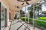 Screened-in lanai featuring tile flooring, dual ceiling fans, and sliding glass door access to the exterior grounds