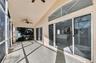 Screened lanai featuring tiled flooring, ceiling fans, vaulted ceilings, and expansive sliding glass doors with transom windows