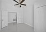 High-ceiling interior featuring polished tile flooring, a multi-blade ceiling fan with integrated lighting, and white paneled doors