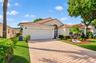 Single-story residence featuring a terracotta-tile roof, paved driveway, two-car garage, stucco exterior, and arched entryway with decorative metal sc