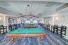 Recreational space featuring a drop ceiling, multi-light tiered chandelier, wall-mounted sconces, and patterned carpet flooring