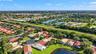 Aerial perspective of residential property featuring a tiled roof, multi-car garage, expansive green space, and water frontage