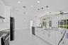 Kitchen featuring a central island with a waterfall countertop, white cabinetry, matte black hardware, recessed lighting, and modern pendant fixtures
