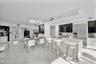 Open-concept kitchen and living area featuring high-gloss cabinetry, stone-finish countertops, stainless steel appliances, and large-format polished f