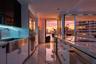 Modern kitchen featuring sleek white cabinetry, stainless steel apron-front sink, polished stone countertops, integrated stainless steel appliances, a