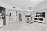 Open living space featuring high-gloss large-format flooring, custom multi-arm chandelier, decorative glass block wall accent, and recessed ceiling li