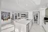 Kitchen featuring a central island with a solid-surface countertop, an integrated electric cooktop, and an under-counter wine refrigerator, complement