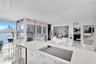 Open-concept kitchen featuring an island with a quartz countertop, an integrated glass cooktop, a built-in under-counter beverage refrigerator, and fl