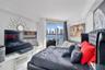 Floor-to-ceiling glass sliding doors opening to a balcony, white stone-finish flooring, recessed ceiling lighting, and crown molding