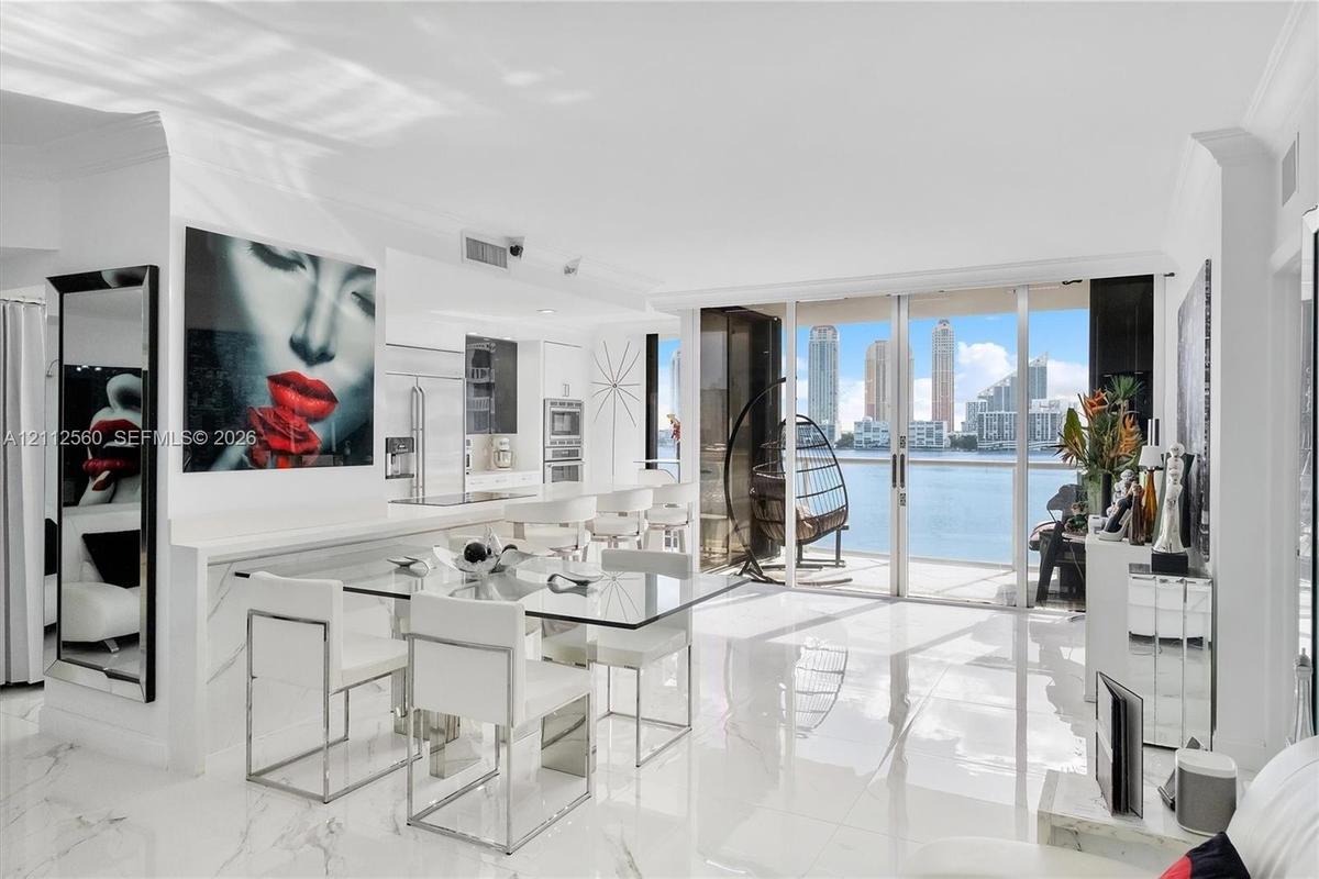 Open-concept living space featuring high-gloss stone-finish flooring, floor-to-ceiling glass sliding doors, and white cabinetry