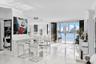 Open-concept living space featuring high-gloss stone-finish flooring, floor-to-ceiling glass sliding doors, and white cabinetry