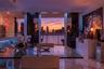 Floor-to-ceiling sliding glass doors, stone-finish flooring, built-in cabinetry, and integrated kitchen appliances, complemented by a water and citysc