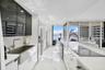 Kitchen featuring high-gloss cabinetry, stainless steel farmhouse sink, white stone-surfaced countertops, built-in appliances, and floor-to-ceiling wi