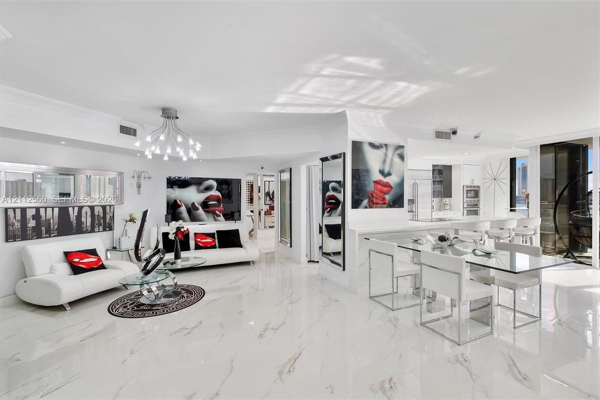 Open-concept living space featuring high-gloss large-format tile flooring, multi-arm chandelier lighting, sleek built-in cabinetry, and integrated kit