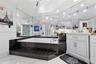 Sunken jetted tub finished with black linear tile, white cabinetry with silver hardware, full-width wall mirrors, recessed lighting, and large-format 
