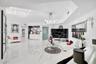 Large-format polished flooring, recessed ceiling lighting, multi-arm chandelier, built-in wet bar with high-gloss cabinetry, and frosted glass door