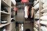 Custom closet system featuring floor-to-ceiling wood-finish shelving, multiple hanging rods, and integrated drawer storage