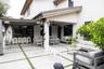 Covered patio featuring a built-in outdoor bar, large-format paver hardscaping with turf infill, a ceiling fan, and exterior wall-mounted lighting