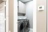 Laundry closet featuring custom wood-finish cabinetry, solid surface shelving, and a wall-mounted digital climate control thermostat