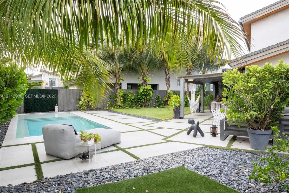 Outdoor living space featuring an in-ground swimming pool, large format concrete pavers with artificial turf inlay, covered patio area, and perimeter 