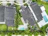 Aerial perspective of a multi-story residence featuring a rectangular swimming pool, integrated hardscaped patio, manicured lawn, and mature perimeter