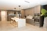 Kitchen featuring wood-finish flat-panel cabinetry, a waterfall island with stone countertop, stainless steel built-in double wall ovens, stainless st