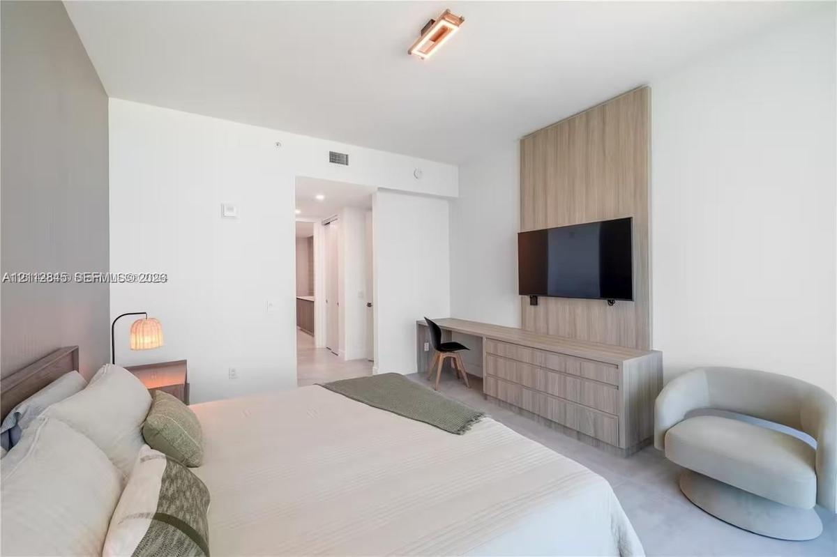 Custom floor-to-ceiling wood-finish wall paneling, integrated built-in cabinetry, streamlined desk workstation, and modern rectangular flush-mount cei