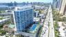 High-rise residential building featuring a glass facade, expansive wrap-around balconies, a structured podium base with decorative relief, and a recre