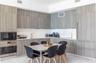Kitchen featuring flat-panel wood-finish cabinetry, integrated refrigerator, built-in stainless steel microwave and wall oven, and light-toned solid s