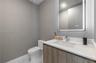 Modern vanity with integrated rectangular sink and quartz countertop, complemented by a lighted rectangular mirror, textured wall covering, and stone-
