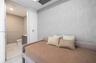 Textured accent wall, neutral interior palette, and recessed ceiling lighting, with an entry to a bathroom featuring stone-finish floor tiling and a f