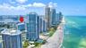 Aerial perspective featuring coastal high-rise structures, direct oceanfront proximity, and sandy beach access