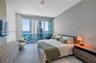 Floor-to-ceiling glass sliding doors, large-format tile flooring, built-in wall paneling, and an integrated balcony with glass railing