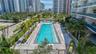 Rectangular swimming pool featuring integrated entry steps and stone paver decking surrounded by mature palm trees and glass-railed balconies