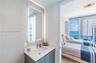 Vanity featuring a stone-composite countertop, undermount sink, integrated LED-backlit mirror, and wood-finish cabinetry, paired with floor-to-ceiling