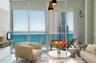 Floor-to-ceiling glass sliding doors, private balcony with metal railing, pendant light fixture with tiered shades, and custom built-in shelving
