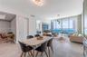 Open-concept interior featuring large-format tile flooring, floor-to-ceiling glass walls, and a balcony with an ocean backdrop