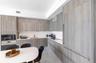 Kitchen featuring flat-panel wood-finish cabinetry, integrated panel-ready refrigerator, solid-surface countertops, built-in microwave, and flush-moun