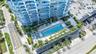 High-rise building featuring curvilinear architecture with glass balcony railings, an expansive ground-level swimming pool, a dedicated spa, and integ