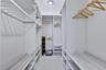 Walk-in closet featuring floor-to-ceiling white built-in shelving, adjustable storage racks, integrated hanging rods, and glossy tile flooring