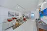 Open-concept living space featuring high-gloss tile flooring, recessed ceiling lighting, a custom stone-clad media wall, and an arched glass door