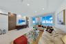 Living area featuring floor-to-ceiling windows, porcelain tile flooring, recessed ceiling lighting, and a decorative wall treatment with vertical wood