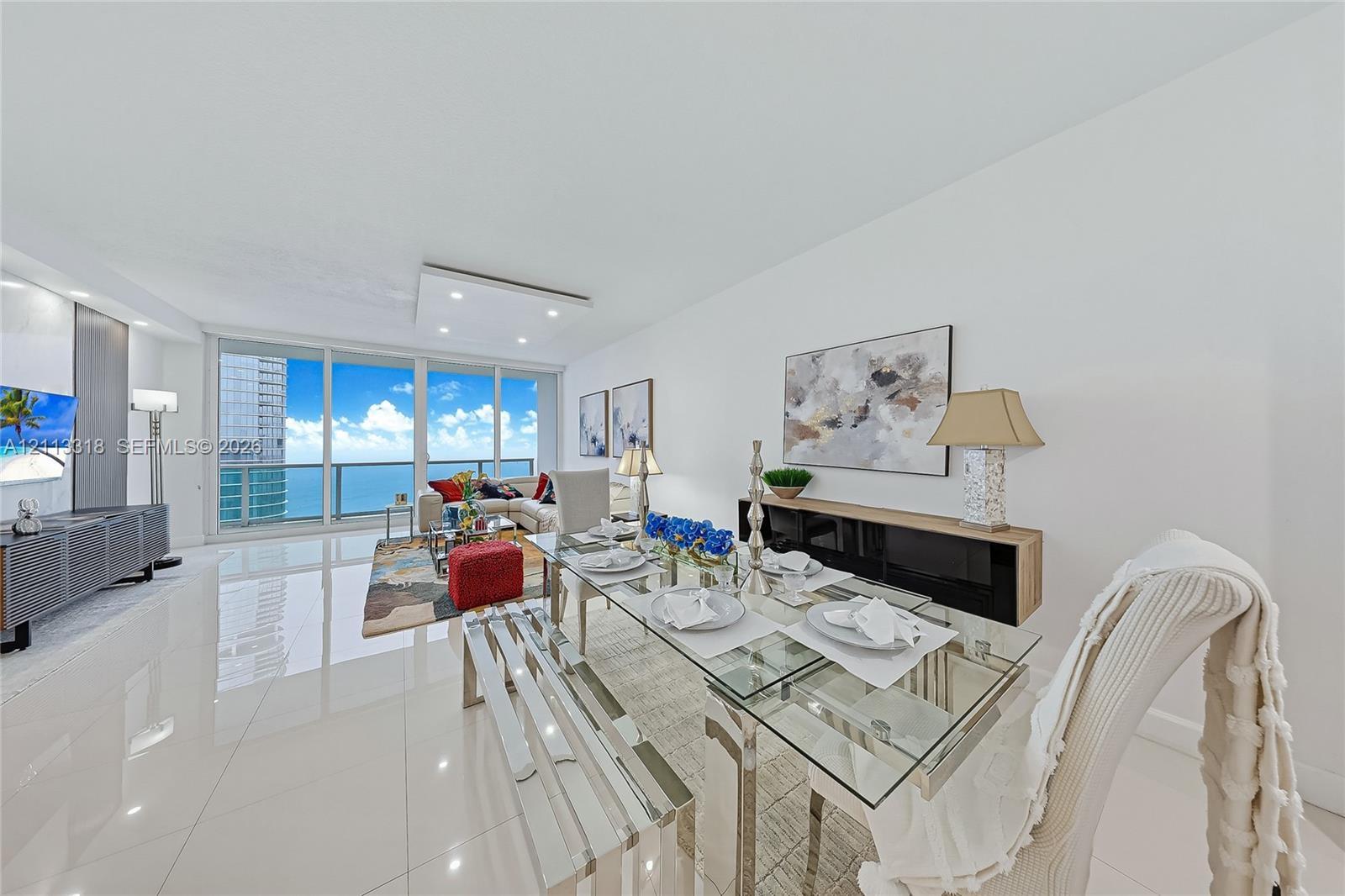 Open-concept interior featuring large-format tile flooring, recessed ceiling lighting, and floor-to-ceiling glass panel walls